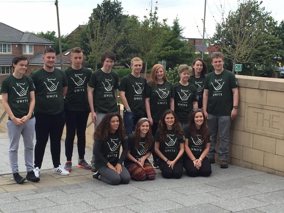 A group of young adults wearing matching t-shirts with the word "unite" printed on them, posing together for a photograph.